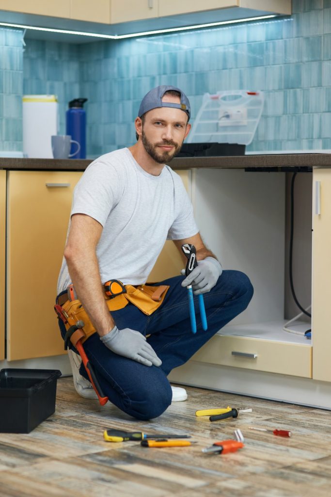 full length shot of young handyman professional plumber wearing tool belt looking at camera while